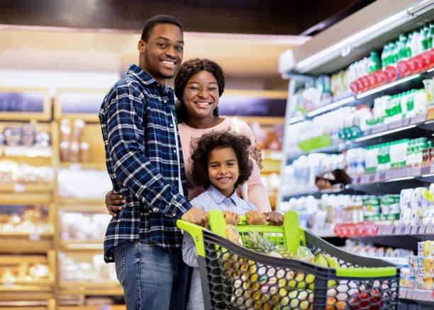 A family shopping together, pushing a cart of fresh produce down an aisle
